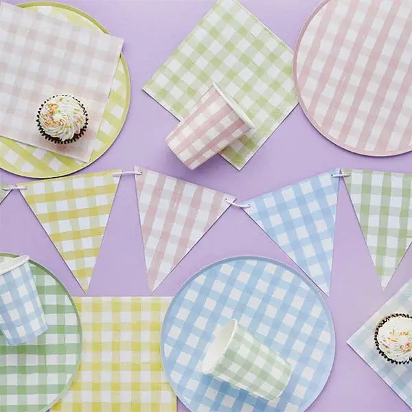 Pastel gingham party tableware with checkered plates, cups, napkins, and bunting in soft pink, blue, yellow, and green tones